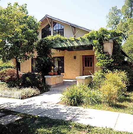 A natural arbor and generous overhangs, above, protect rammed-earth walls in high rainfall areas.